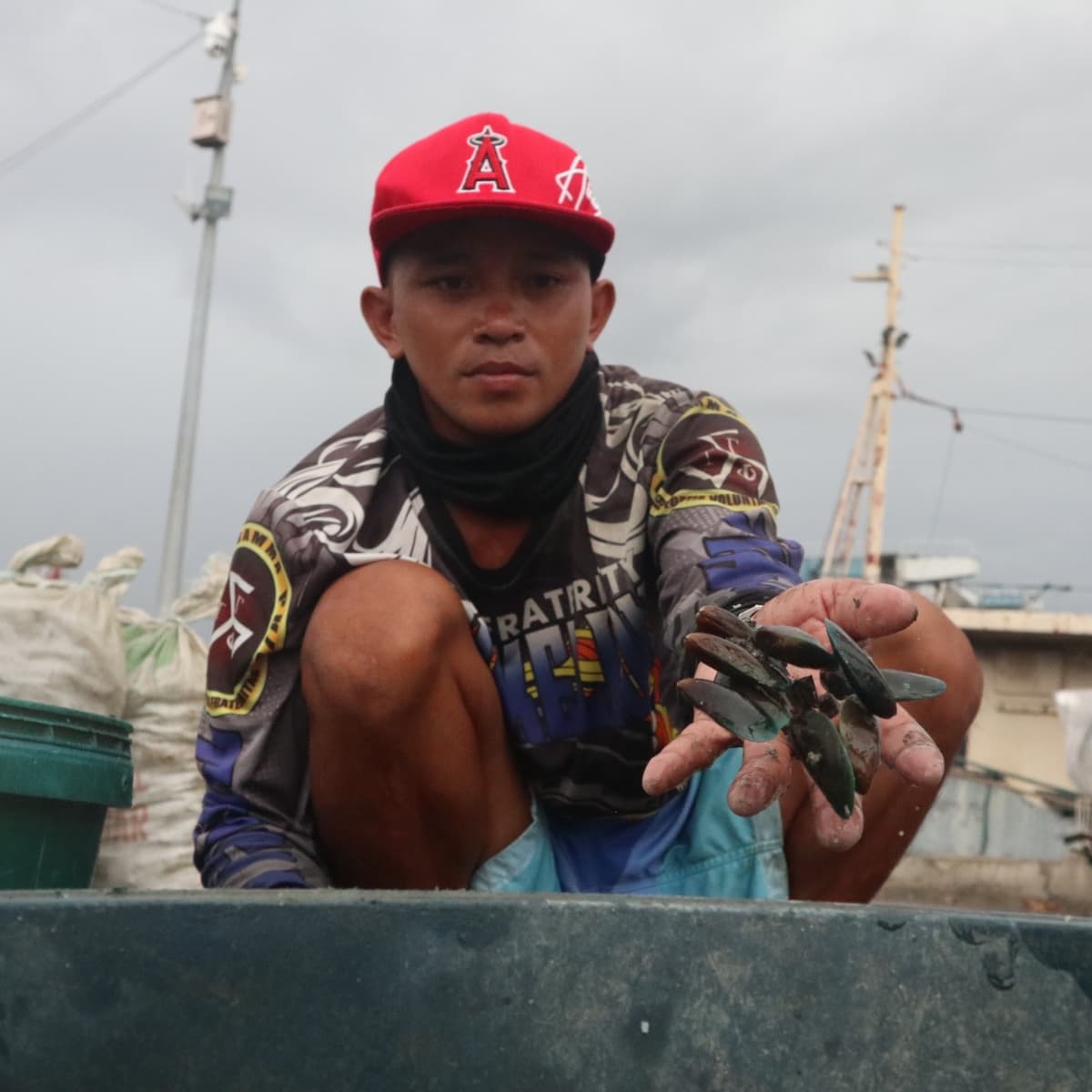 A mussel farmer who requested to be identified as Lito, 27, sorts freshly harvested mussels at Pier Kwatro in Navotas City, where fisherfolk bring their catch before it is sold to traders. (Photo by: Zaijan Rio Tengson)